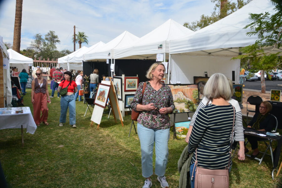 A woman standing next to an art show.